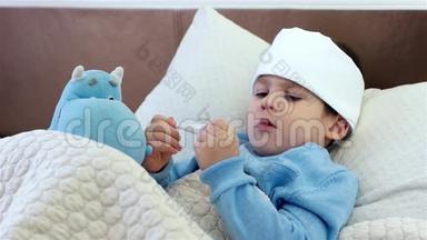 孩子咳嗽，男孩脖子上戴着围巾，孩子玩电子体温计，躺在床上，高温